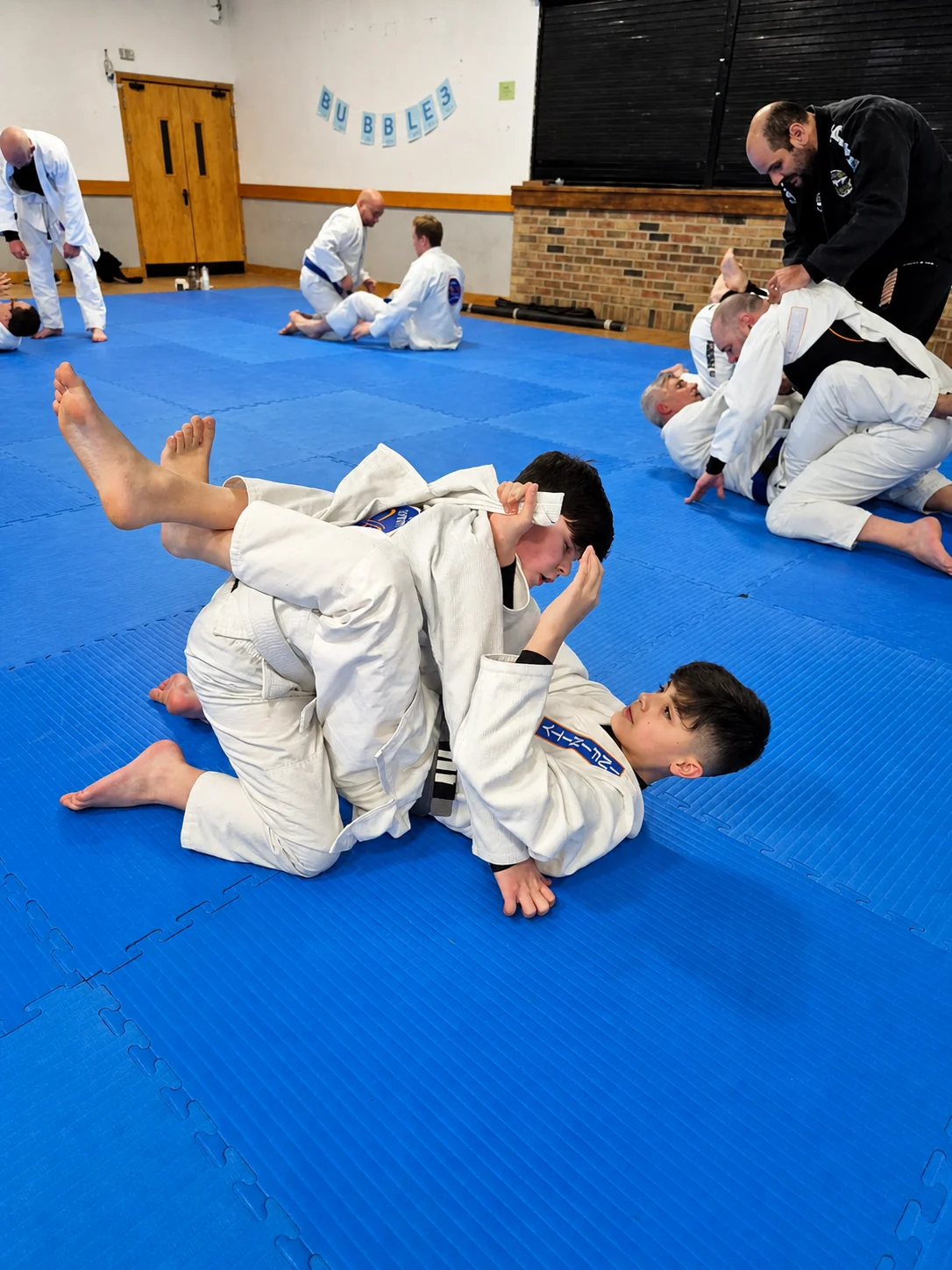 Two Junior Academy students practising ground jiu-jitsu technique during class at Infinity Jiu-Jitsu