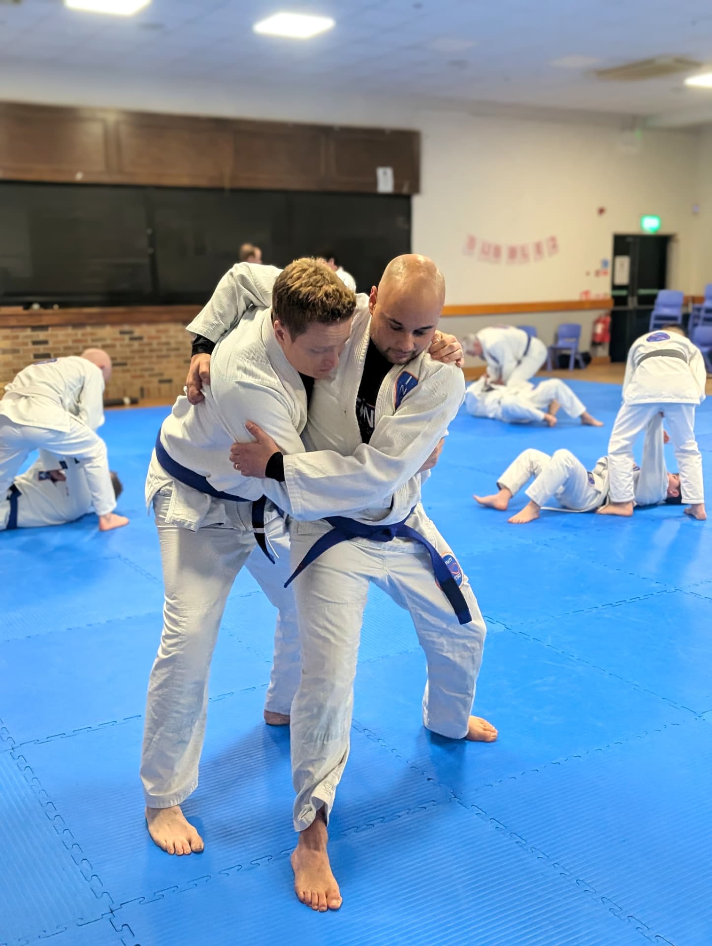 Two adult students practising a standing technique calmly during a regular class