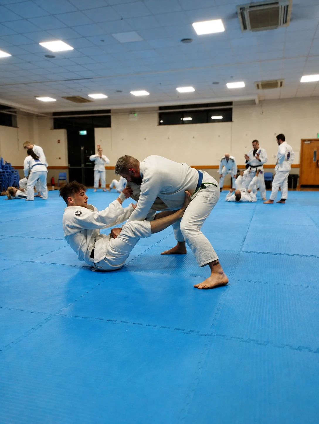 An instructor giving one-to-one coaching to a young student during a class at Infinity Jiu-Jitsu