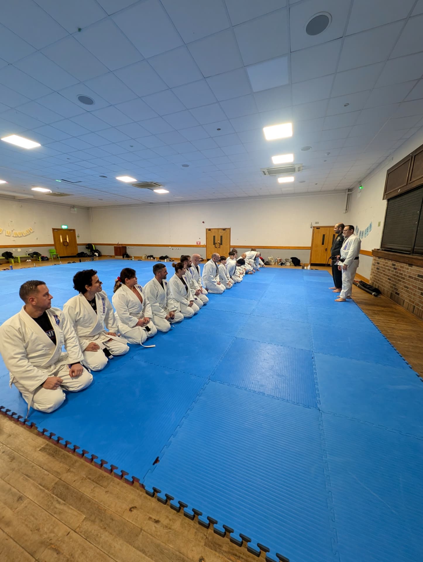 Adult students lined up on the mats at the start of an Infinity class