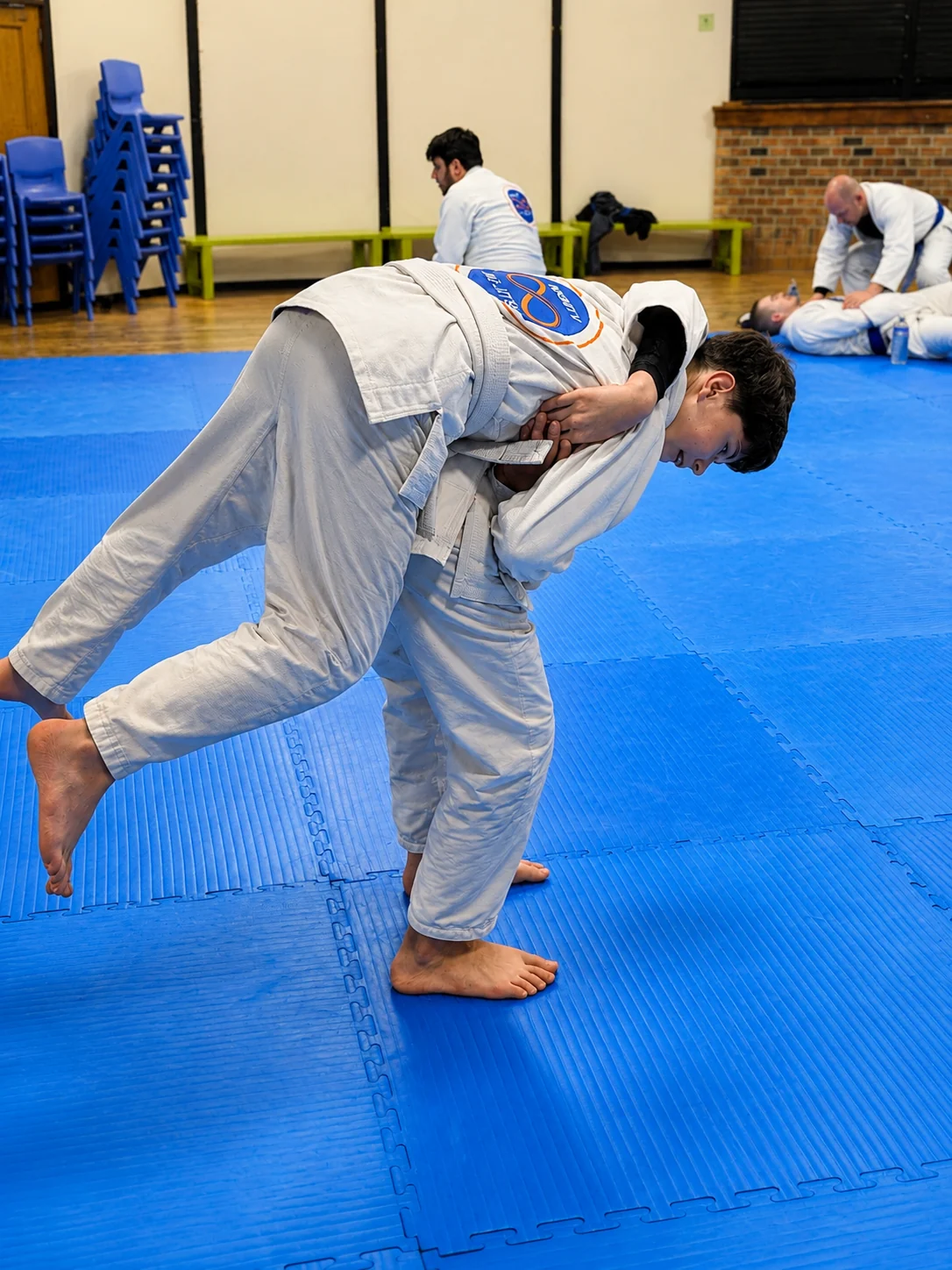 Two Junior Academy students practising a standing takedown on the mats at Infinity Jiu-Jitsu