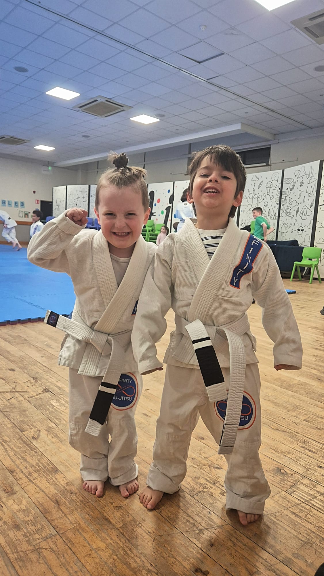Two young Little Champions in Infinity gis smiling and celebrating together after class