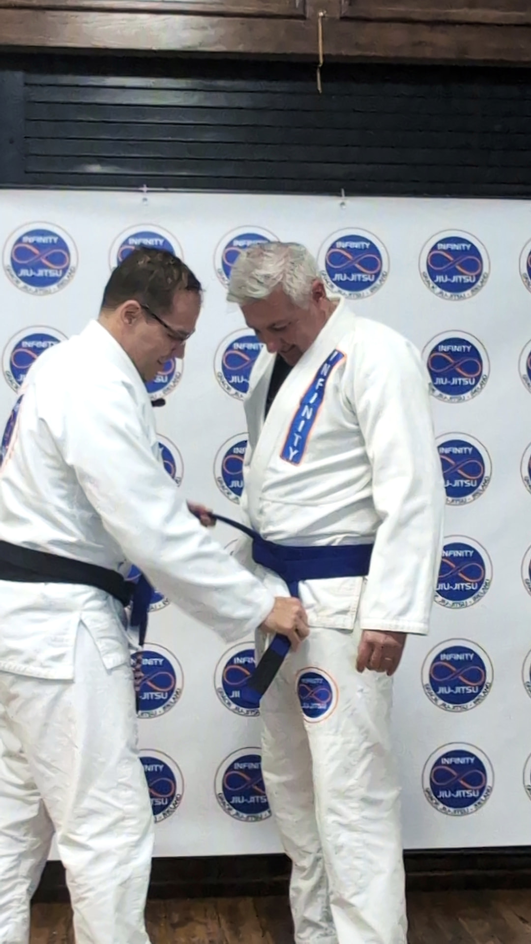 Professor Fabiano presenting a blue belt to an adult Infinity Jiu-Jitsu student in Portmarnock.